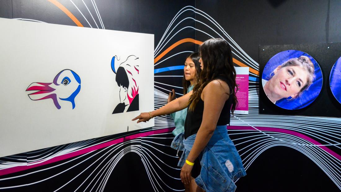 Two girls pointing at and touching an illusion exhibit display
